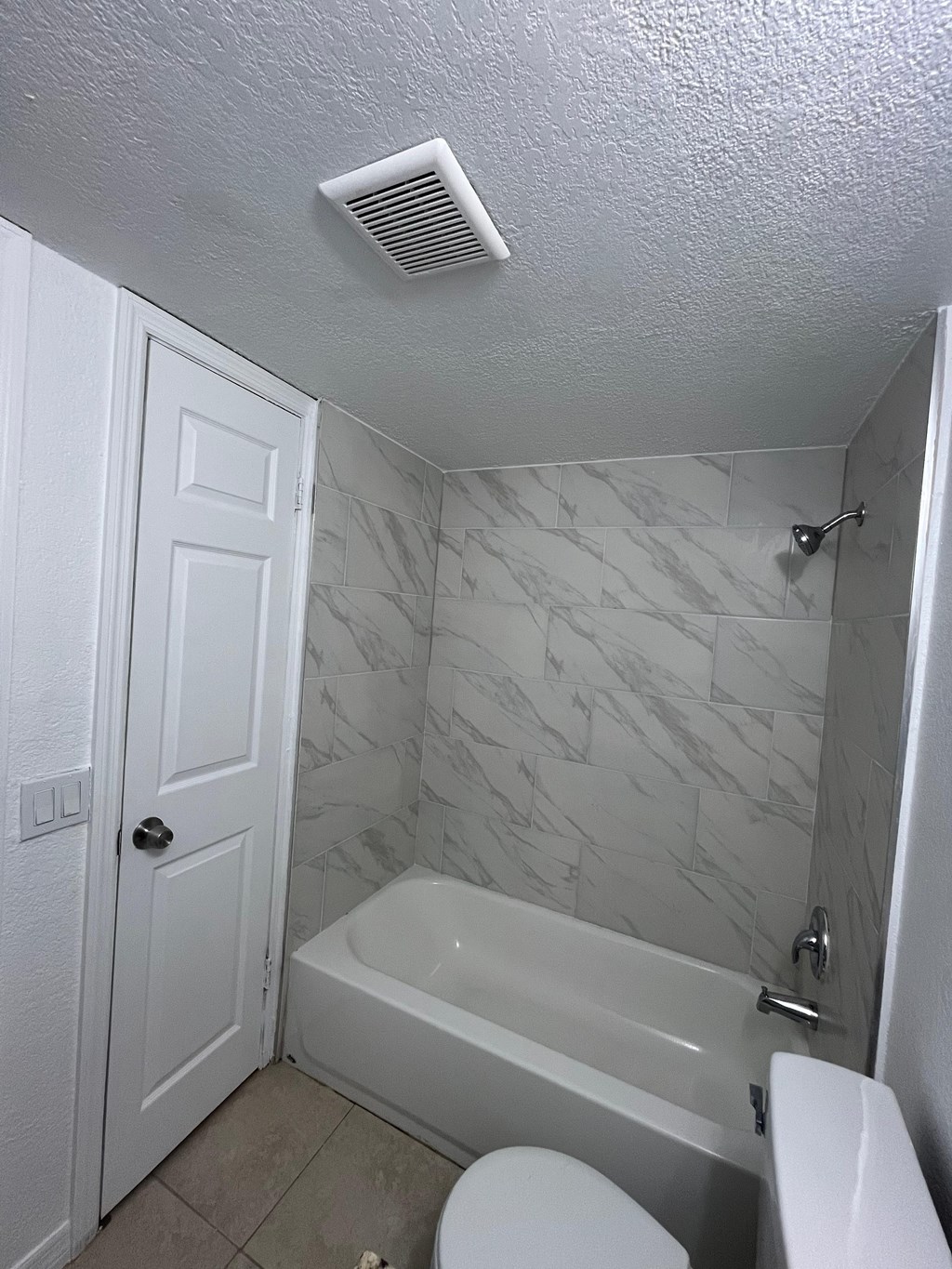 A white bathroom with a toilet, tub, and shower.