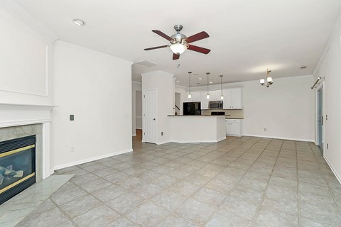 A spacious living room with a fireplace and a ceiling fan.