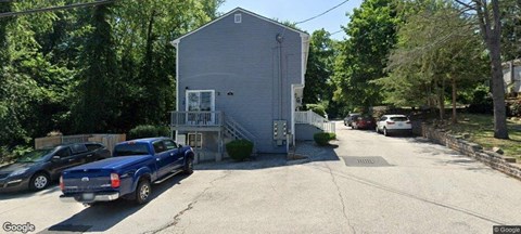 A blue truck is parked in front of a two-story house.