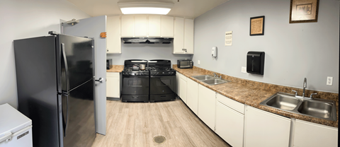 A black refrigerator is in a kitchen with a black stove and black oven.