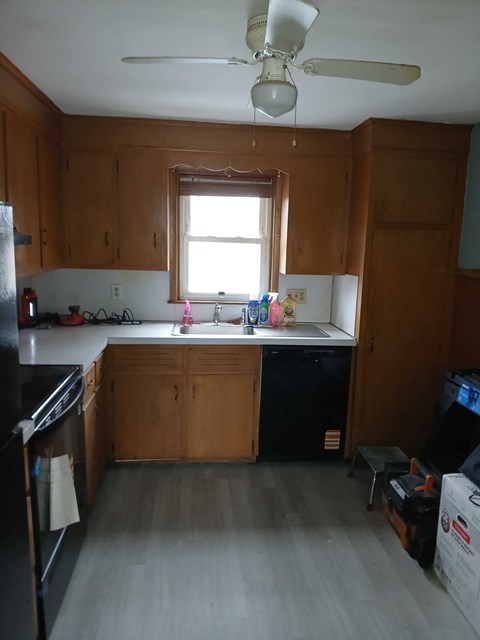A kitchen with wooden cabinets and a black fridge.