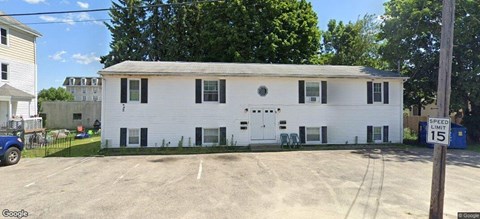 A white two-story building with a black door and windows.