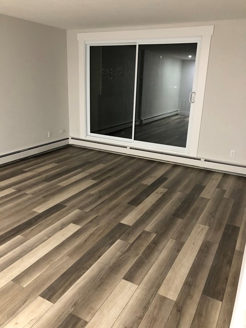 A room with a sliding glass door and wooden flooring.