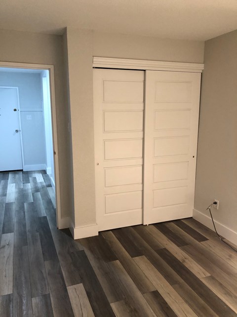A room with a white door and a wooden floor.