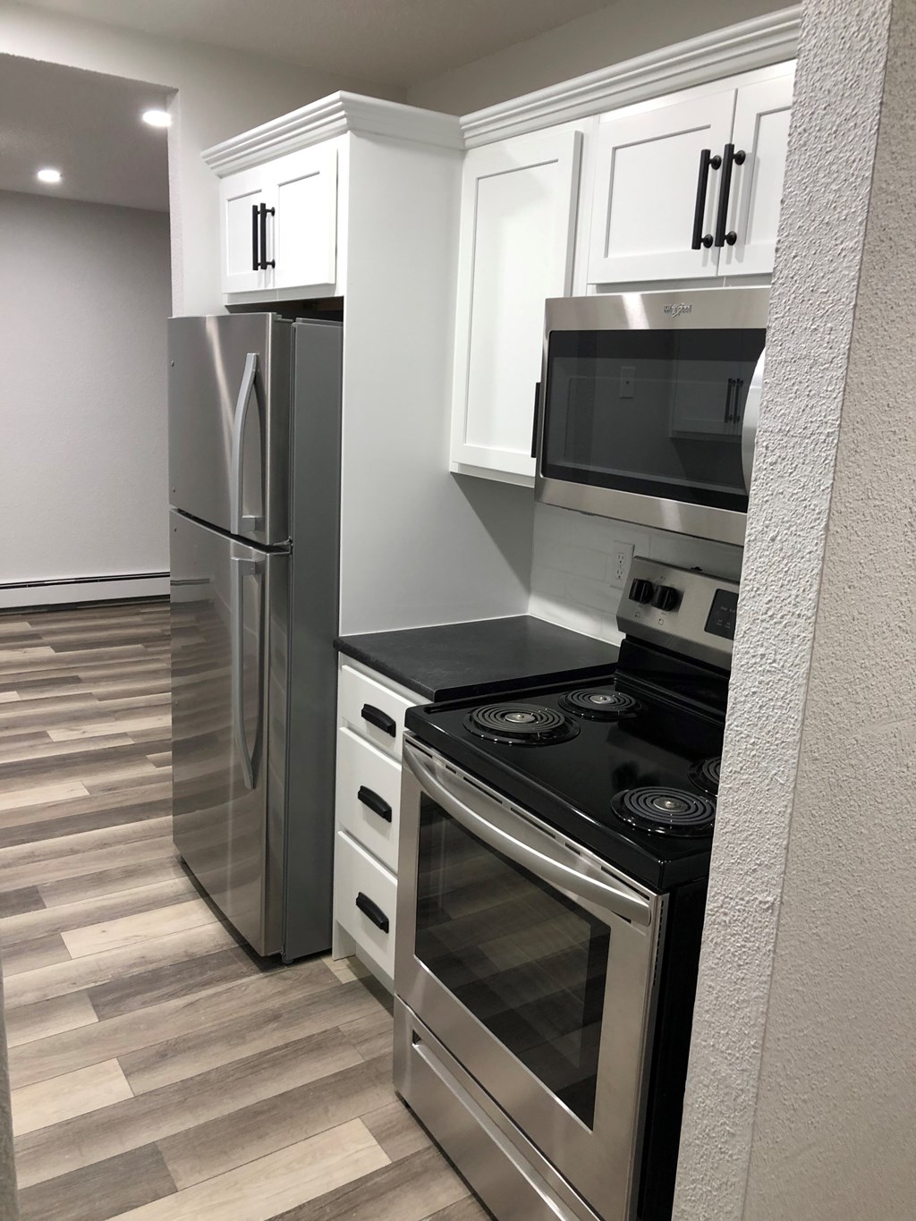 A modern kitchen with a stainless steel refrigerator, microwave, and oven.
