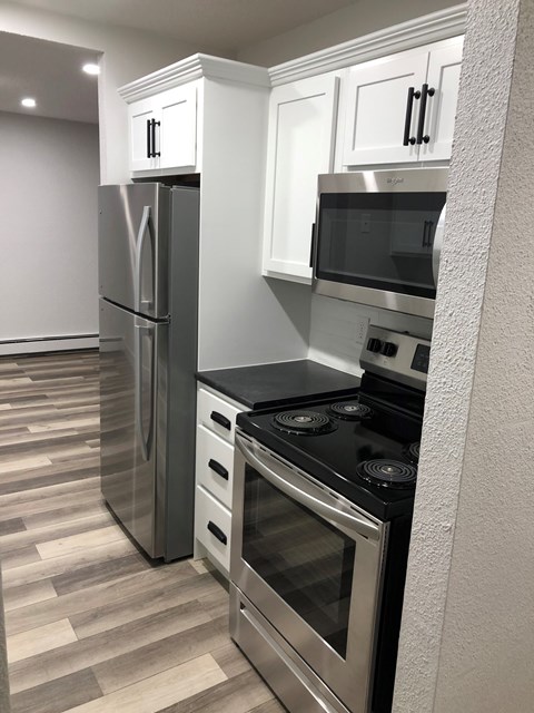 A modern kitchen with a stainless steel refrigerator, microwave, and oven.
