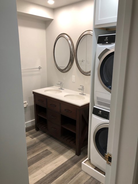 A bathroom with a white sink and a washer and dryer.