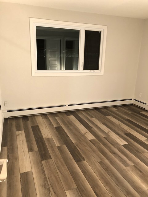 A room with a window and wooden flooring.
