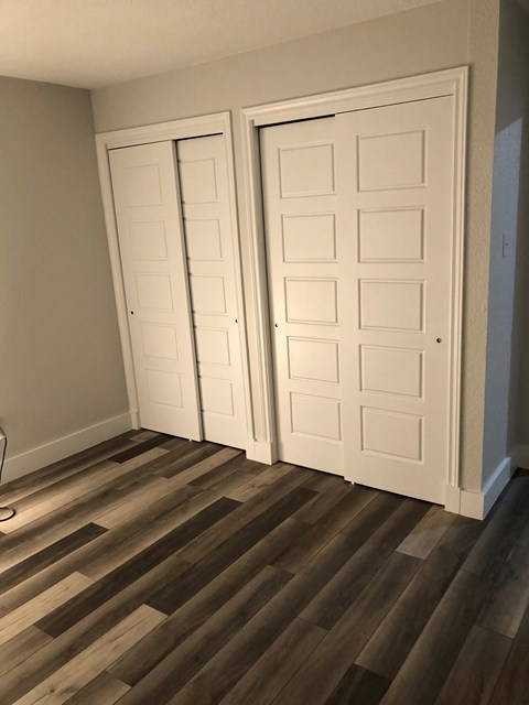 A room with two white doors and wooden flooring.