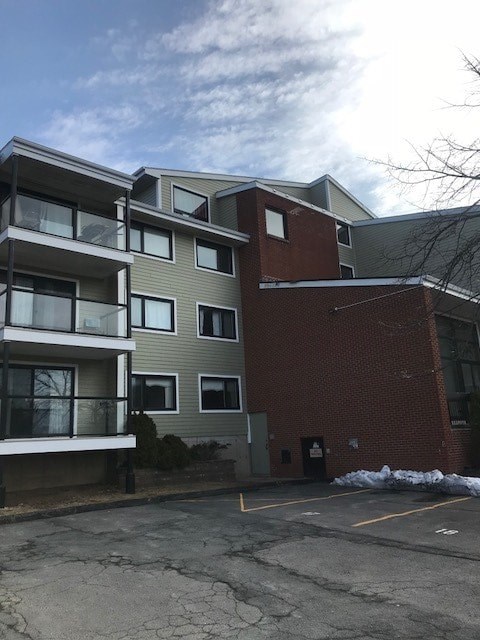 A building with a grey and red facade is surrounded by a parking lot.
