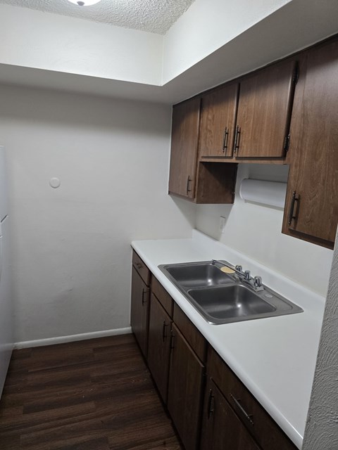 A kitchen with a sink and brown cabinets.
