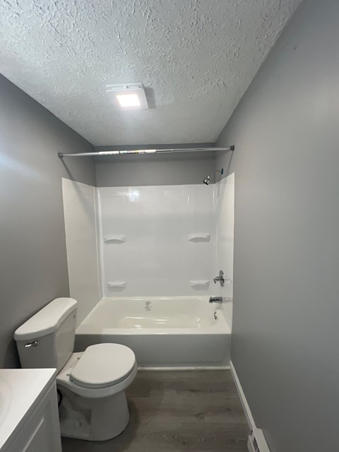 A white toilet sits next to a walk-in shower in a small bathroom.