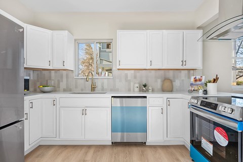 A kitchen with white cabinets and a blue dishwasher.