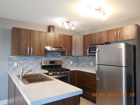 A kitchen with a stove, sink, and refrigerator.