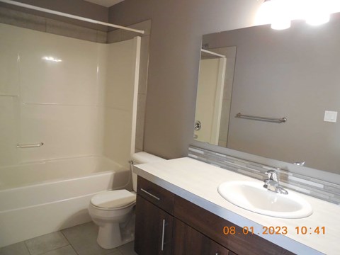 A bathroom with a toilet, sink, and mirror.