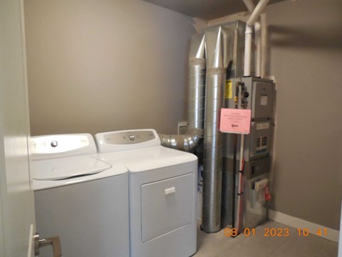 A bathroom with a washer and dryer and a water heater.