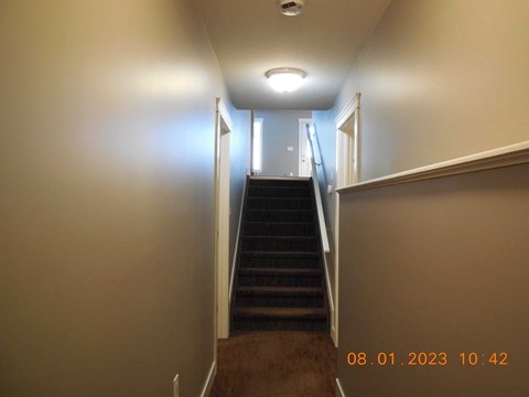 A staircase with a light on the side and a door at the top.