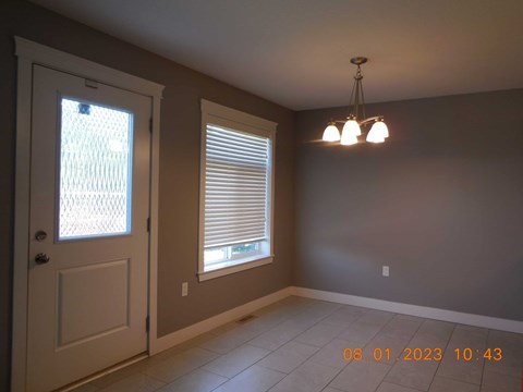 A room with a door, window with blinds, and a light fixture.