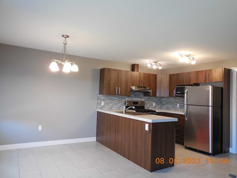 A kitchen with a stainless steel refrigerator and wooden cabinets.