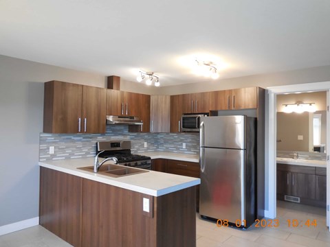 A kitchen with a refrigerator, sink, and cabinets.