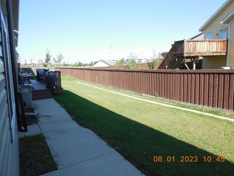 A backyard with a wooden fence and a green lawn.