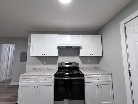 A kitchen with white cabinets and a black stove top oven.