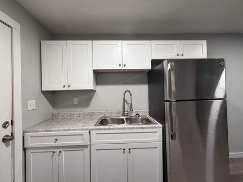 A kitchen with white cabinets and a stainless steel refrigerator.