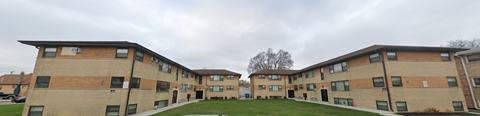 Apartment complex with brown and beige buildings and green lawns.