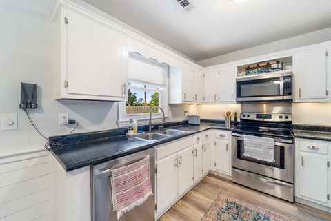 A kitchen with white cabinets and a black countertop.