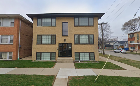 A brown and beige brick building with a black door and windows.