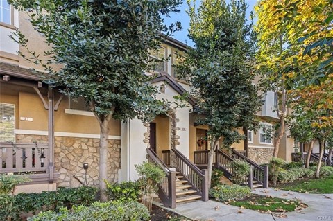 A house with a brown front porch and a stone wall.