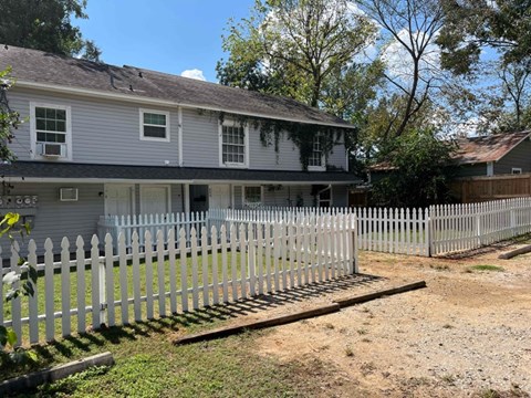 A house with a grey roof and white picket fence.