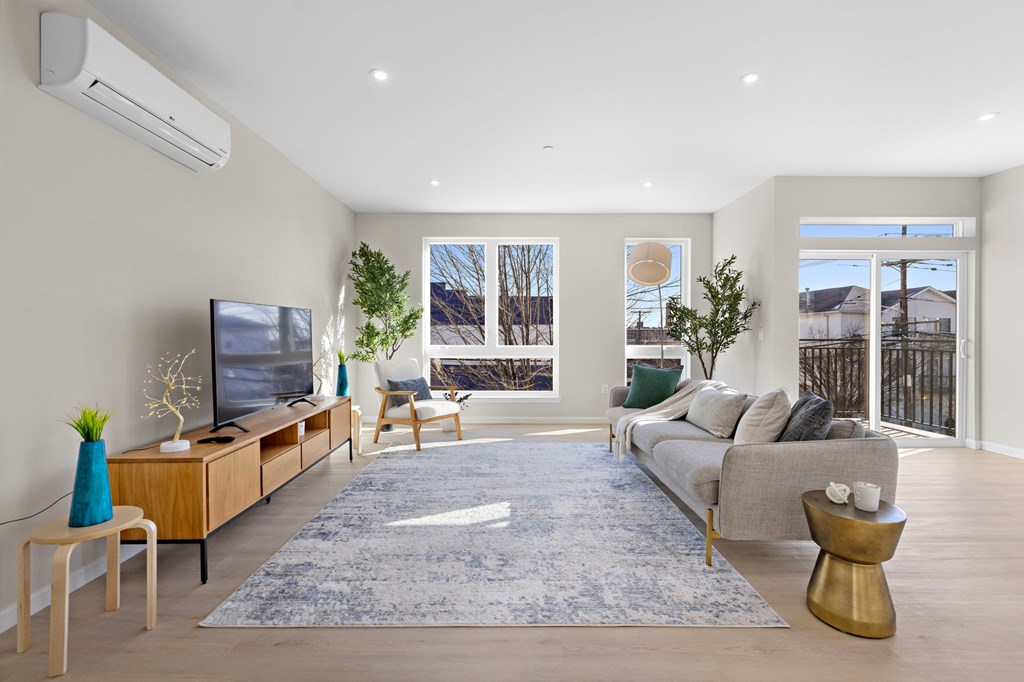 A modern living room with a large couch, a TV, and a rug.