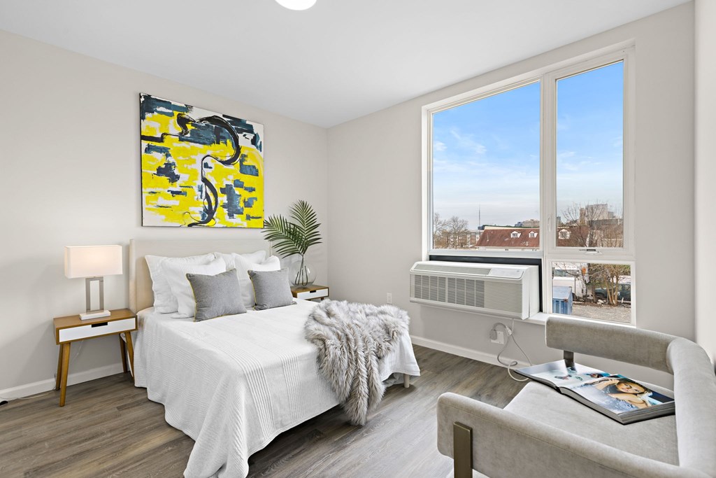 A bedroom with a bed, chair, and a painting on the wall.