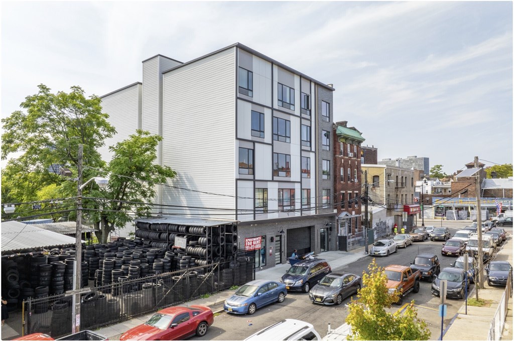 A street view of a city with cars parked on the side of the road and a building in the background.