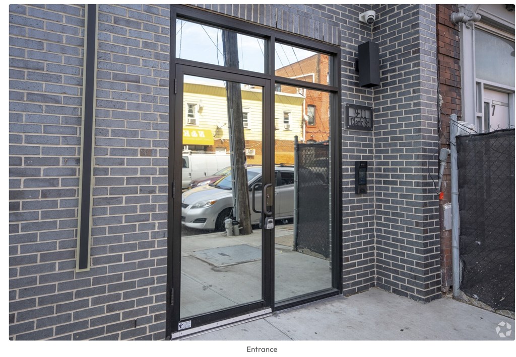 A grey brick wall with a glass door entrance.