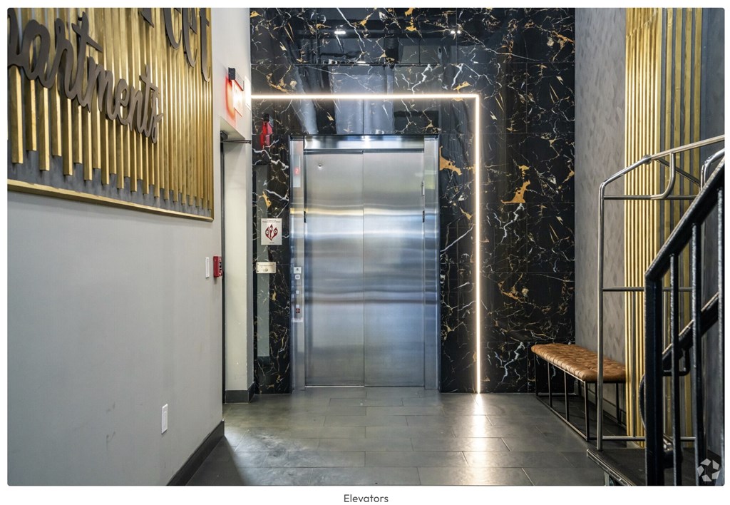 A hallway with a marble floor and a staircase on the right.