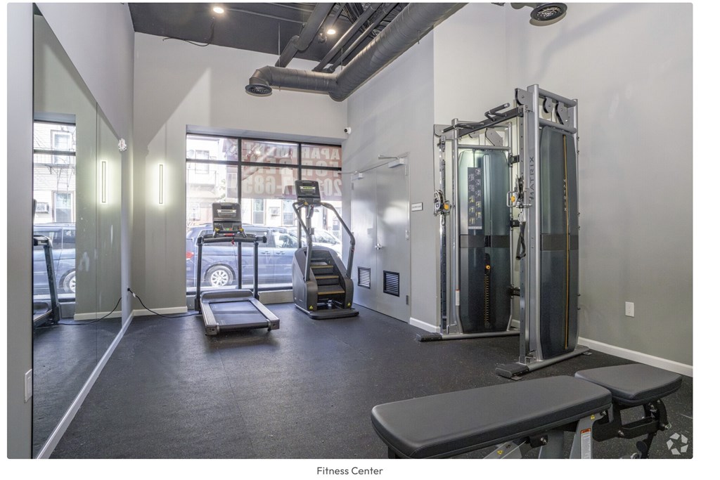 A fitness center with a variety of equipment including a treadmill, a bench, and a squat rack.