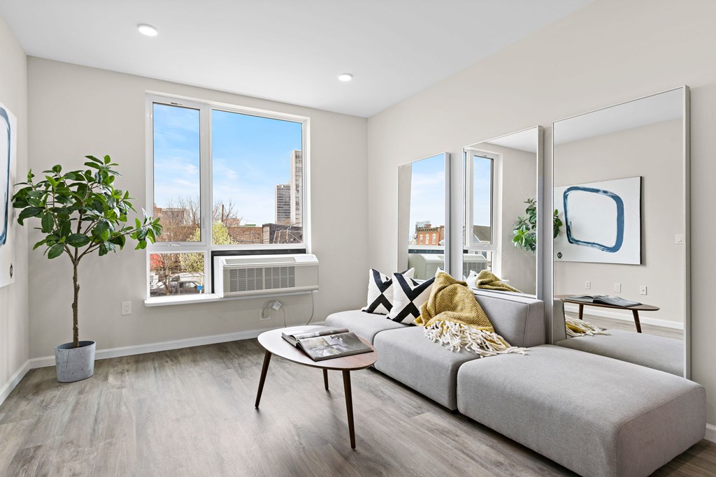 A living room with a grey couch, a coffee table, and a potted plant.