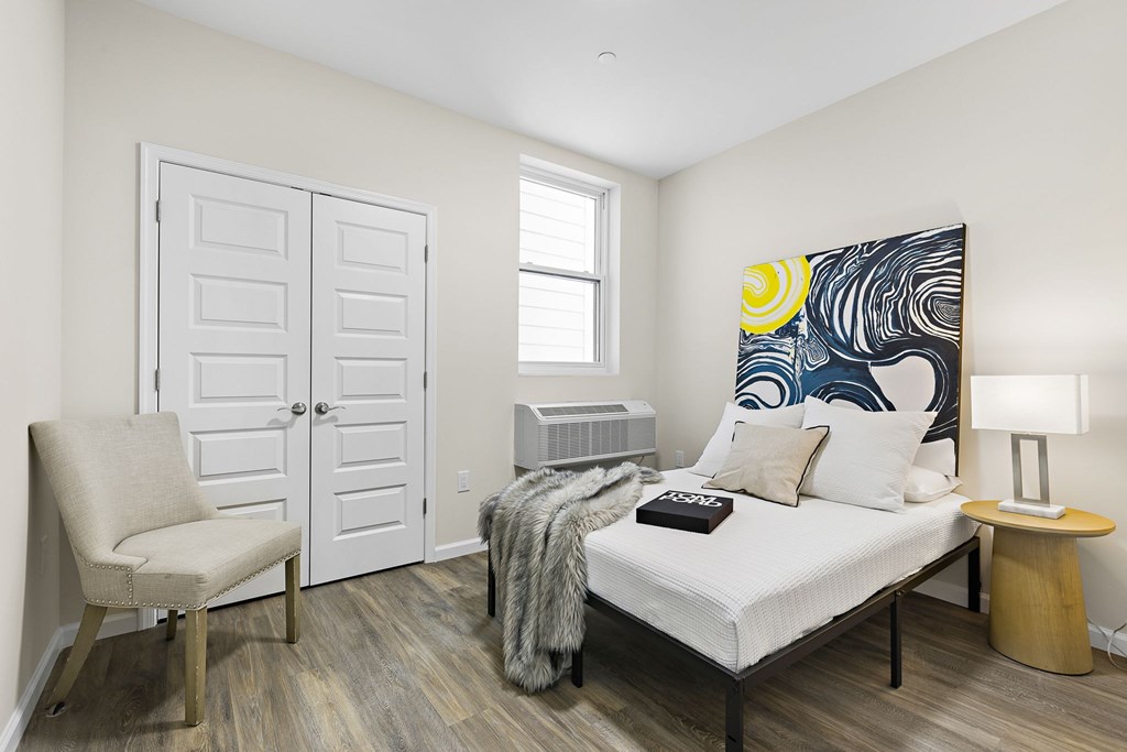 A bedroom with a bed, chair, and painting on the wall.