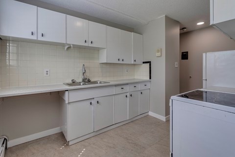 A kitchen with white cabinets and a white counter top.