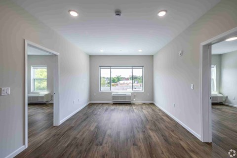 A spacious room with wooden floors and a large window.