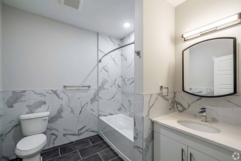 A bathroom with a marble patterned floor and walls.