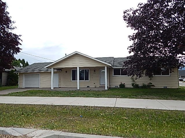A beige house with a white garage door and a grey roof.