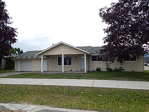 A beige house with a white garage door and a grey roof.