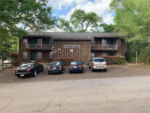 A parking lot with four cars and a building in the background.