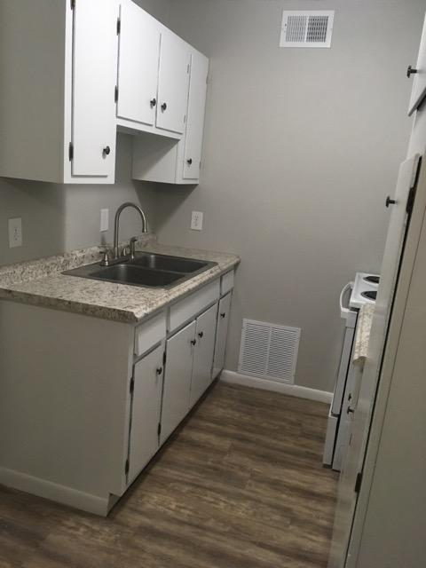 A kitchen with white cabinets and a sink.