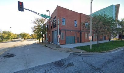 A red brick building is situated at a street corner with a traffic light.