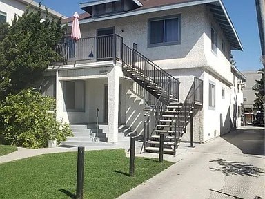 A white house with a black metal staircase.