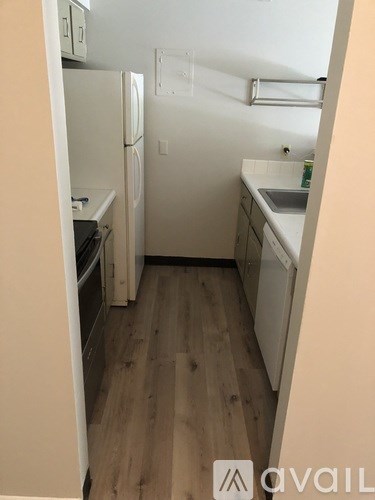 A small kitchen with a refrigerator, sink, and oven.